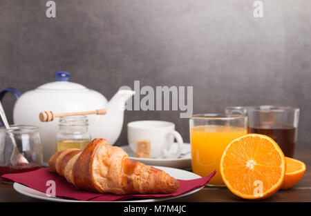 Des croissants sur une table de petit déjeuner avec jus de fruits et du café et des fruits frais. Banque D'Images