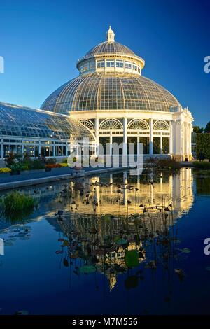 Jardin Botanique de New York, dans le Bronx, New York, USA : l'Enid A. Haupt Conservatory (1902) reflète dans une piscine couverte de nénuphars. Banque D'Images