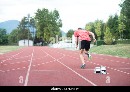 Homme Sprinter fonctionnant sur les voies cyclables rouge en athlétisme et à vitesse élevée du stade Vue d'en haut Banque D'Images