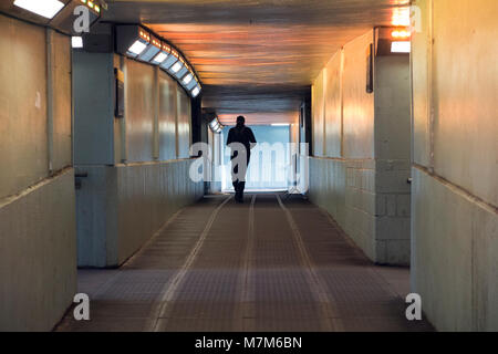 Un homme marche à travers un tunnel lumineux Banque D'Images