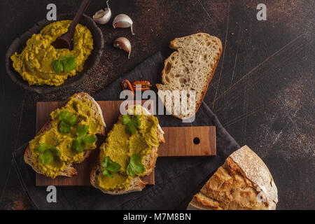 Petits pois hoummos sandwichs sur un fond sombre. La nourriture végétalienne saine concept. Banque D'Images