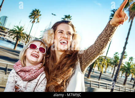 À Barcelone pour un sourire parfait. d'hiver la mère et l'enfant moderne les touristes sur le quai à Barcelone, Espagne pointant sur quelque chose Banque D'Images