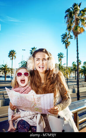 À Barcelone pour un hiver parfait. Portrait de la mère et de l'enfant moderne heureux voyageurs à Barcelone, Espagne avec la carte Banque D'Images