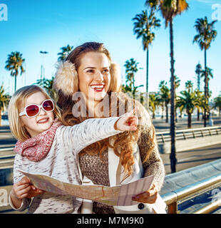 À Barcelone pour un hiver parfait. smiling modern mother and daughter touristes à Barcelone, Espagne holding map and pointing Banque D'Images