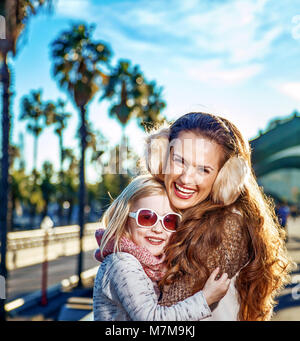 À Barcelone pour un hiver parfait. smiling modern mother and daughter touristes sur le quai à Barcelone, Espagne hugging Banque D'Images