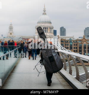 Retour de l'artiste de rue musical non identifiables à l'envers d'un violoncelle sur le Millennium Bridge donnant sur la Cathédrale St Paul Banque D'Images