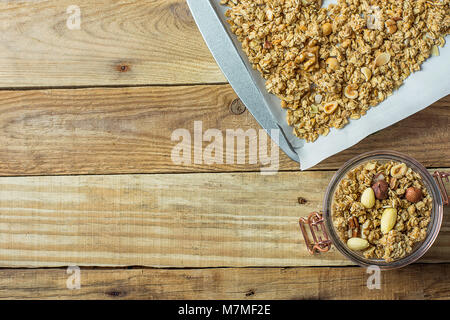 Avec l'Avoine Muesli muesli maison Amandes Noisettes Noix mélange sur une plaque recouverte de papier de Trey et dans un bocal en verre. Bois vieilli d'examen. Vue supérieure de la FLA Banque D'Images