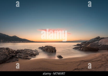 Coucher du soleil sur l'éperon rocheux et plage de sable à Algajola en Balagne Corse Banque D'Images