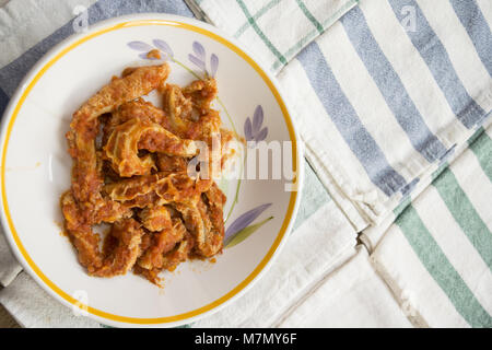 Les tripes de style romain avec la sauce tomate dans un plat sur quelques serviettes colorées Banque D'Images