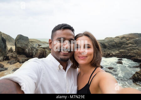 Young caucasian woman and man asiatique au cours de selfies lune de miel au Sri lanka on beach Banque D'Images