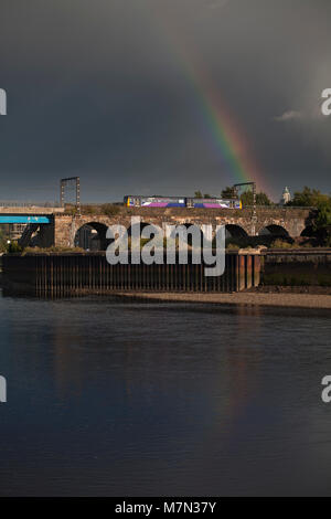 Northern Rail un train passe de la classe 142, Défaut de pont de Carlisle, Lancaster, sur la rivière Lune avec un Lancaster - train Morecambe avec un arc-en-ciel Banque D'Images