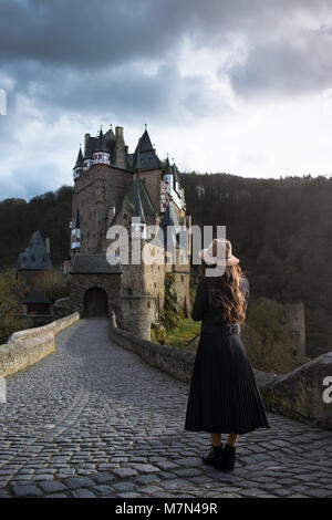 Jeune femme est méconnaissable sur route menant à un château magnifique. Lieu médiéval fantastique. Trendy girl est voyager en Europe Banque D'Images