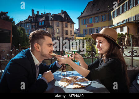 Jeune femme petit ami d'alimentation. Deux personnes élégant se trouve ensemble dans les cafés avec de la nourriture et du vin. L'homme à la combinaison mange pizza avec petite amie en Alsace Banque D'Images