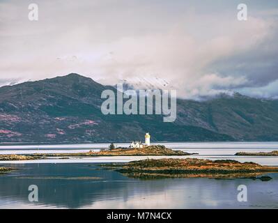 Phare sur Isle Ornsay, de la rive sud de l'île de Skye, en Ecosse. Navire de commerce à Rocky island, montagnes en arrière-plan Banque D'Images