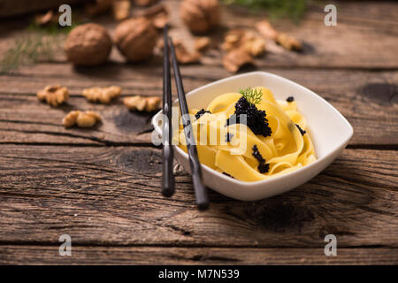 Tagliatelles pâtes caviar sur un bol en bois blanc avec retour au sol. Close up Banque D'Images