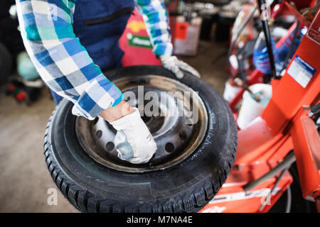 Senior female mechanic repairing une voiture dans un garage. Banque D'Images