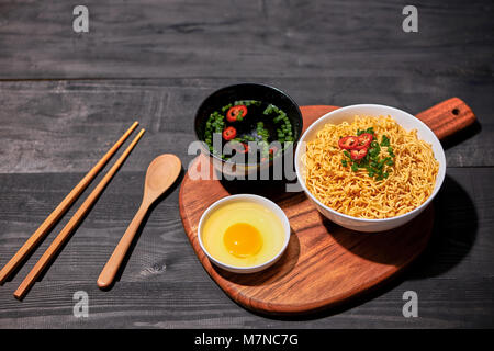 Les nouilles instantanées avec des œufs dans des bols en bois Banque D'Images