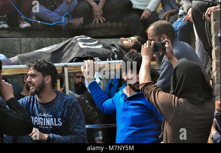 Srinagar, au Cachemire. 12 mars, 2018. Une fille cachemirienne prend une photo du corps de Eesa Fazili, un étudiant en ingénierie tourné durant son militant procession funéraire à Srinagar, Cachemire sous administration indienne. Au milieu des affrontements, des milliers de personnes ont participé dans les derniers sacrements de l'Eesa Fazili, un étudiant en ingénierie tourné militant. Jésus n'a été tué dans une fusillade brève le long avec deux associés dans Hakoora Kashmirâ sud du village, district d'Anantnag plus tôt aujourd'hui. Credit : ZUMA Press, Inc./Alamy Live News Banque D'Images