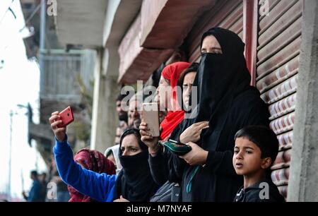 Srinagar, au Cachemire. 12 mars, 2018. Les filles du Cachemire prendre des photos pendant la procession funéraire de l'Eesa Fazili, un étudiant en ingénierie tourné à Srinagar, militant du Cachemire indien. Au milieu des affrontements, des milliers de personnes ont participé dans les derniers sacrements de l'Eesa Fazili, un étudiant en ingénierie tourné militant. Jésus n'a été tué dans une fusillade brève le long avec deux associés dans Hakoora Kashmirâ sud du village, district d'Anantnag plus tôt aujourd'hui. rd dans un énorme crédit : ZUMA Press, Inc./Alamy Live News Banque D'Images