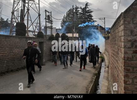 Srinagar, au Cachemire. 12 mars, 2018. Les protestataires Kashmiri Run for Cover lors d'affrontements dans la région de Srinagar, Cachemire sous administration indienne. Au milieu des affrontements, des milliers de personnes ont participé dans les derniers sacrements de l'Eesa Fazili, un étudiant en ingénierie tourné militant. Jésus n'a été tué dans une fusillade brève le long avec deux associés dans Hakoora Kashmirâ sud du village, district d'Anantnag plus tôt aujourd'hui. redit Image Crédit : ZUMA Press, Inc./Alamy Live News Banque D'Images