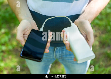 Photo de guy holding phone et powerbank Banque D'Images