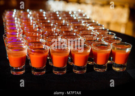 Ensemble de verres avec du jus d'orange disposés en rangées sur le noir sur la table de banquet service traiteur Banque D'Images