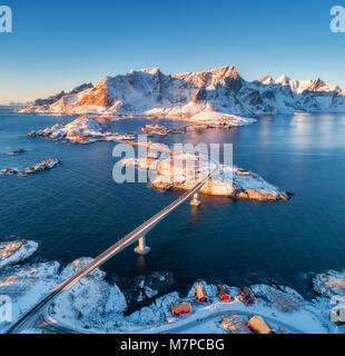 Vue aérienne de Reine et Hamnoy au coucher du soleil en hiver. Des îles Lofoten, Norvège. Paysage panoramique avec bleu de la mer, les montagnes enneigées, les roches, la villa Banque D'Images