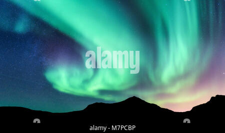 Aurore boréale et silhouette de la montagne. Les îles Lofoten, Norvège. Aurora. Vert et violet northern lights. Ciel avec les étoiles et les lumières polaires. Nuit Banque D'Images