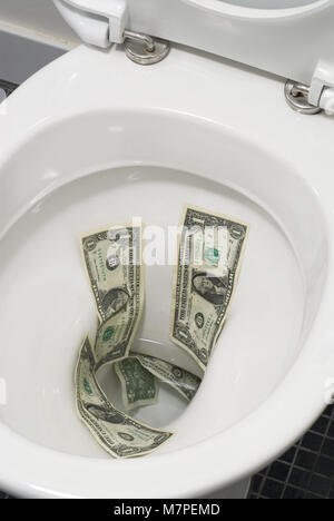 Des dollars jetés dans les toilettes Banque D'Images