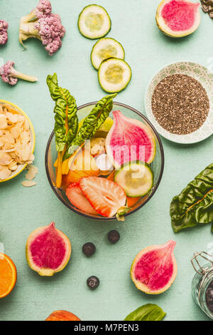 Vue de dessus du malaxeur avec divers fruits et légumes sains ingrédients pour de délicieuses boissons Smoothie Détox ou lumière sur fond de menthe. Suivre un régime, nettoyer Banque D'Images