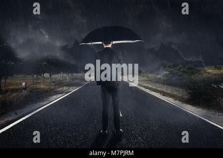 Businessman dans la pluie avec parapluie debout avec fond de nuage sombre Banque D'Images