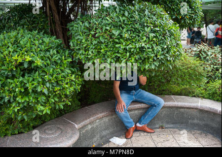 11.03.2018, Singapour, République de Singapour, en Asie - Un homme est assis sous un arbre dans le jardin public de la People's Park Complex dans Chinatown. Banque D'Images