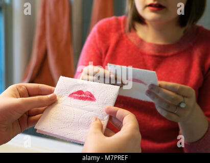 Une adolescente blot son rouge à lèvres sur un mouchoir. Banque D'Images