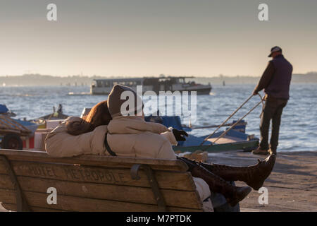 Couple assis sur un banc à l'extérieur de l'hôtel Metropole, Riva degli Schiavoni, Venise à l'ensemble du le bassin de Saint-Marc. Banque D'Images