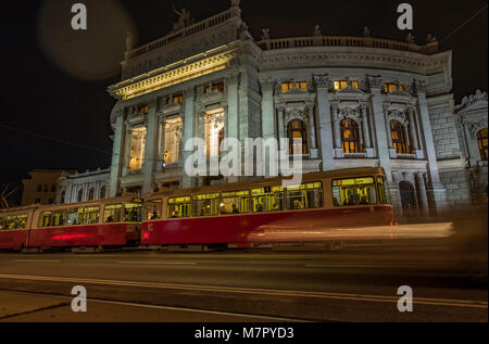 Low angle statique photo de nuit de tram arrivant à l'arrêt en face de Burgtheater de Vienne Banque D'Images