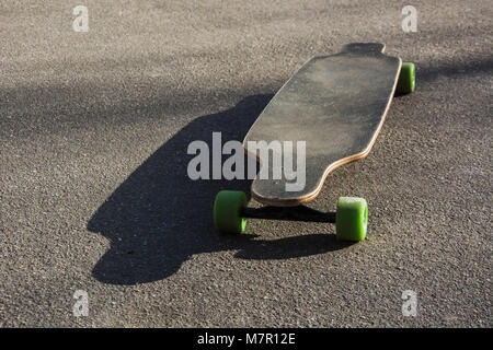 Ancien utilisé longboard isolé sur une route asphaltée. Close up. Banque D'Images