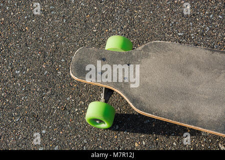 Ancien utilisé longboard isolé sur le terrain. Skateboard noir sur une route asphaltée. Close up. Banque D'Images