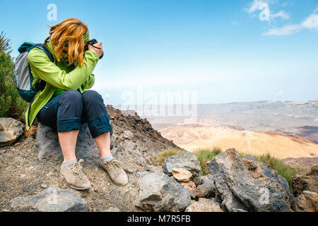 Jeune femme admire une vue magnifique sur la montagne et prend des photos Banque D'Images