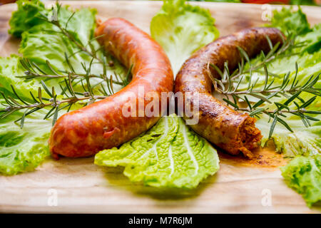 Des saucisses sont décorées avec de la salade verte et des brindilles de romarin. Banque D'Images