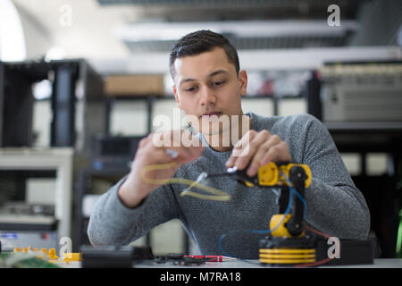 Jeunes adultes en travaillant sur le bras robotique Banque D'Images