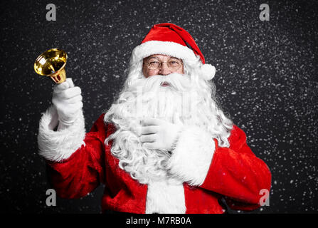 Cheerful santa claus holding pour clochettes Banque D'Images