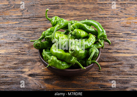 Piment vert placé dans une plaque d'argile sur une table en bois brun Banque D'Images