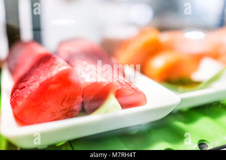 Stand de fruits de mer avec des compressions de rouge rose sauvage d'élevage steaks de thon sur la plaque du bac derrière une vitre présentoir pour sushi sashimi Banque D'Images