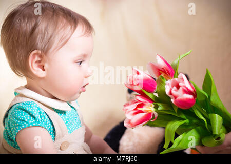 L'âge de 10 mois baby girl looking at flowers Banque D'Images