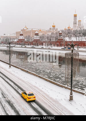 Vue d'hiver du Kremlin de Moscou et la rivière Moskva après les fortes chutes de neige avec une voiture de taxi jaune au premier plan. Banque D'Images