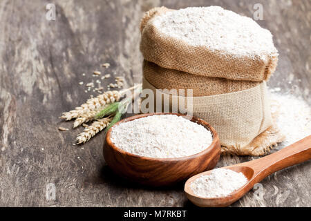 La farine de grains entiers dans un bol en bois et en prenant le bagwith oreilles Banque D'Images