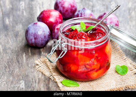 Les prunes cuites avec le caramel et la gousse de vanille dans un bol en verre clair Banque D'Images