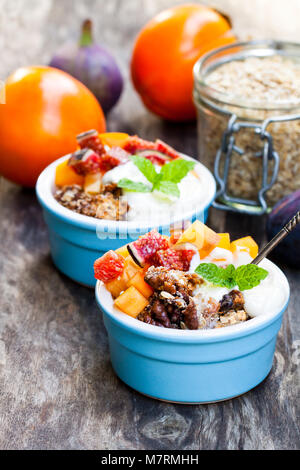 Crumble de fruits avec des flocons d'avoine et kaki et figure sur la table rustique en bois Banque D'Images