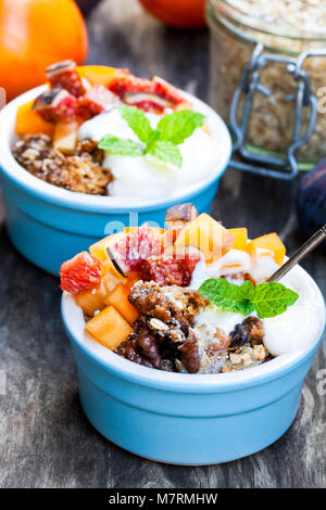 Crumble de fruits avec des flocons d'avoine et kaki et figure sur la table rustique en bois Banque D'Images