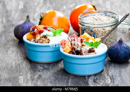 Crumble de fruits avec des flocons d'avoine et kaki et figure sur la table rustique en bois Banque D'Images